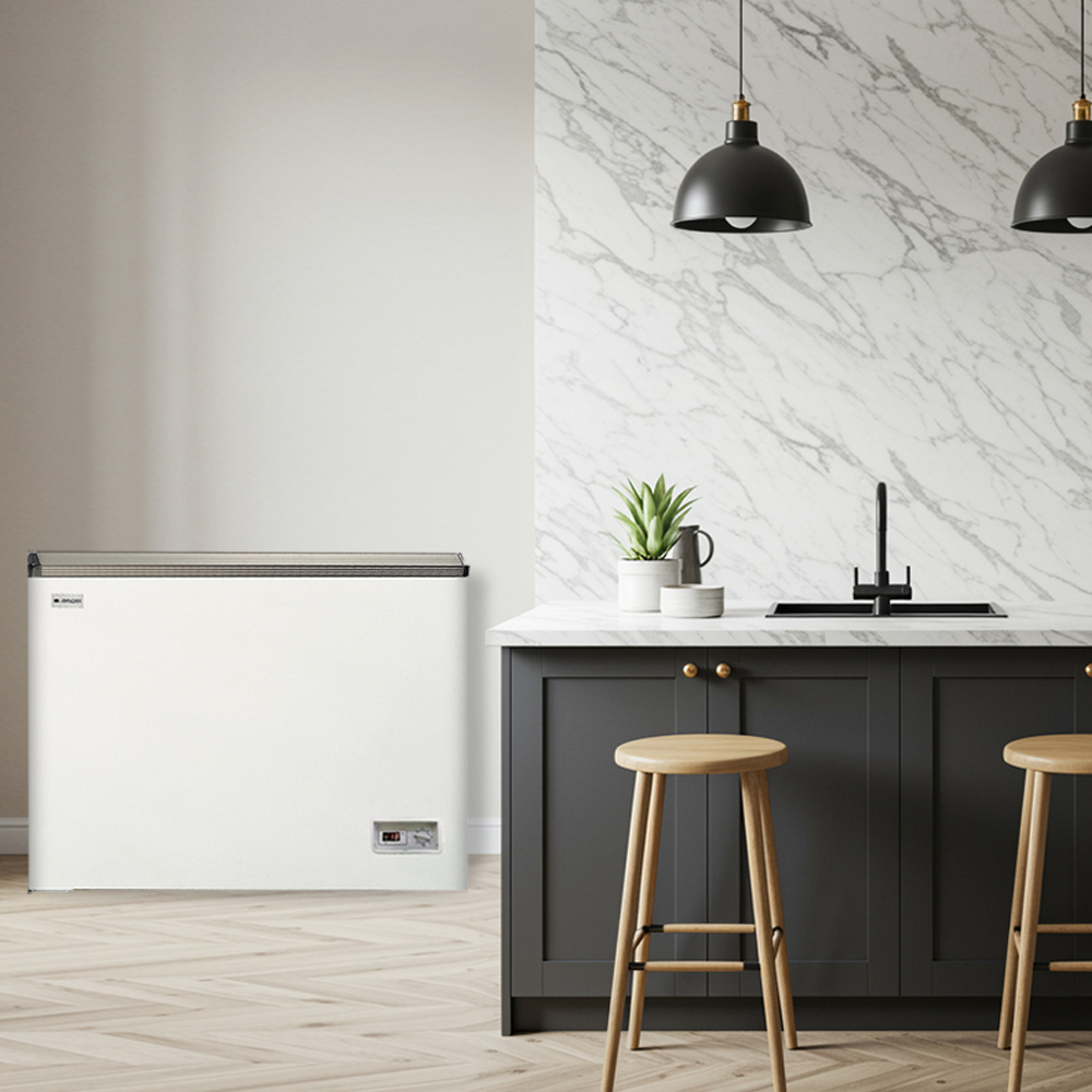 Un congelador horizontal blanco junto a una isla de cocina con taburetes.