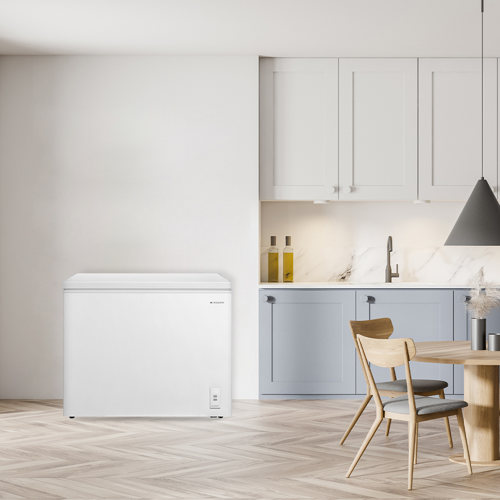 Un congelador horizontal blanco se encuentra en una cocina junto a una mesa.