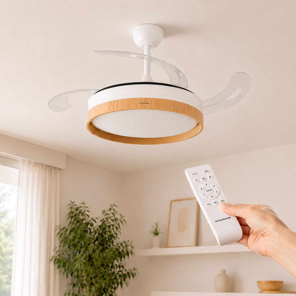 Una lampada ventilatore da soffitto bianca con finiture in legno e telecomando in mano.