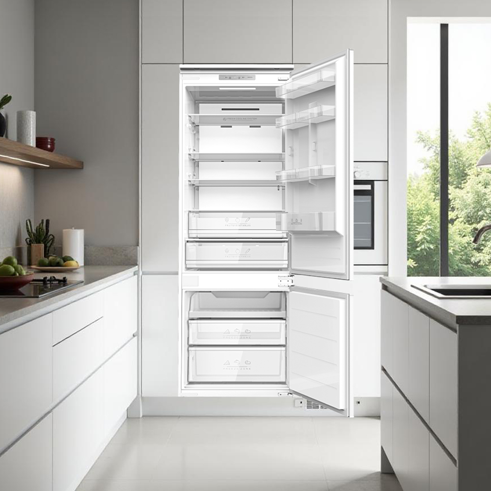 Refrigerador abierto en una cocina moderna con estantes de cristal y cajones.