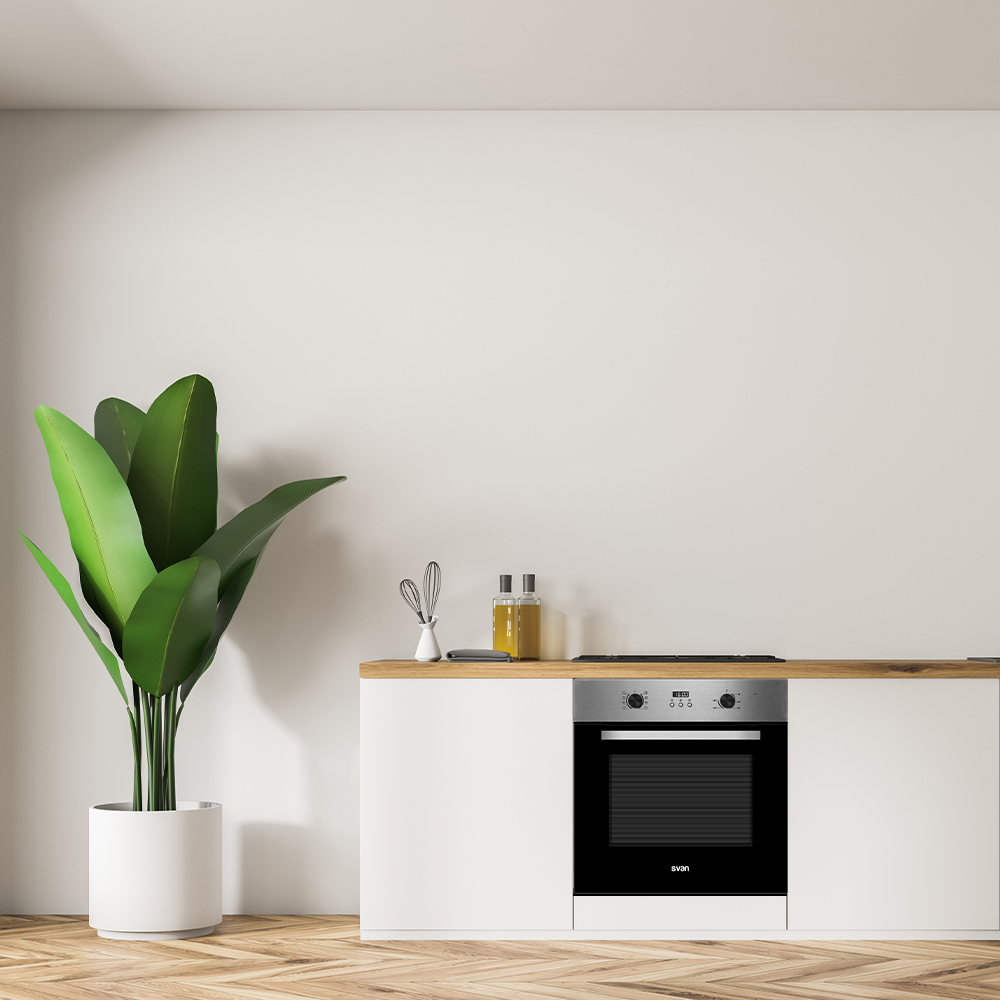 Un mueble de cocina moderno con horno, junto a una planta verde grande.