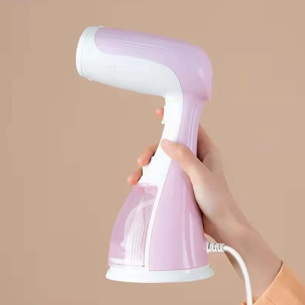 Eine Hand hält einen tragbaren rosa-weißen Kleiderdampfer mit klarem Wassertank.