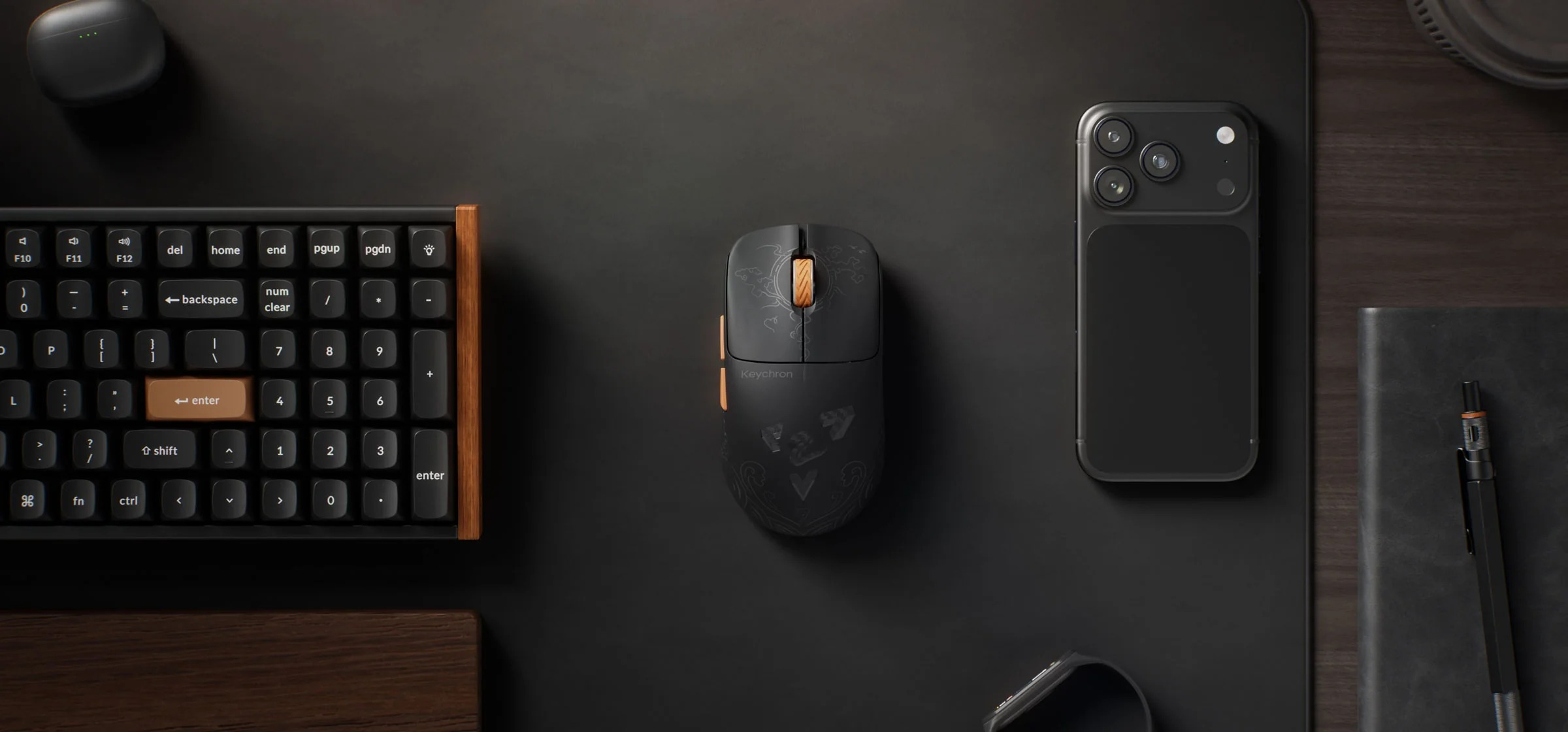 Un teclado, ratón y smartphone negros sobre una alfombrilla negra.