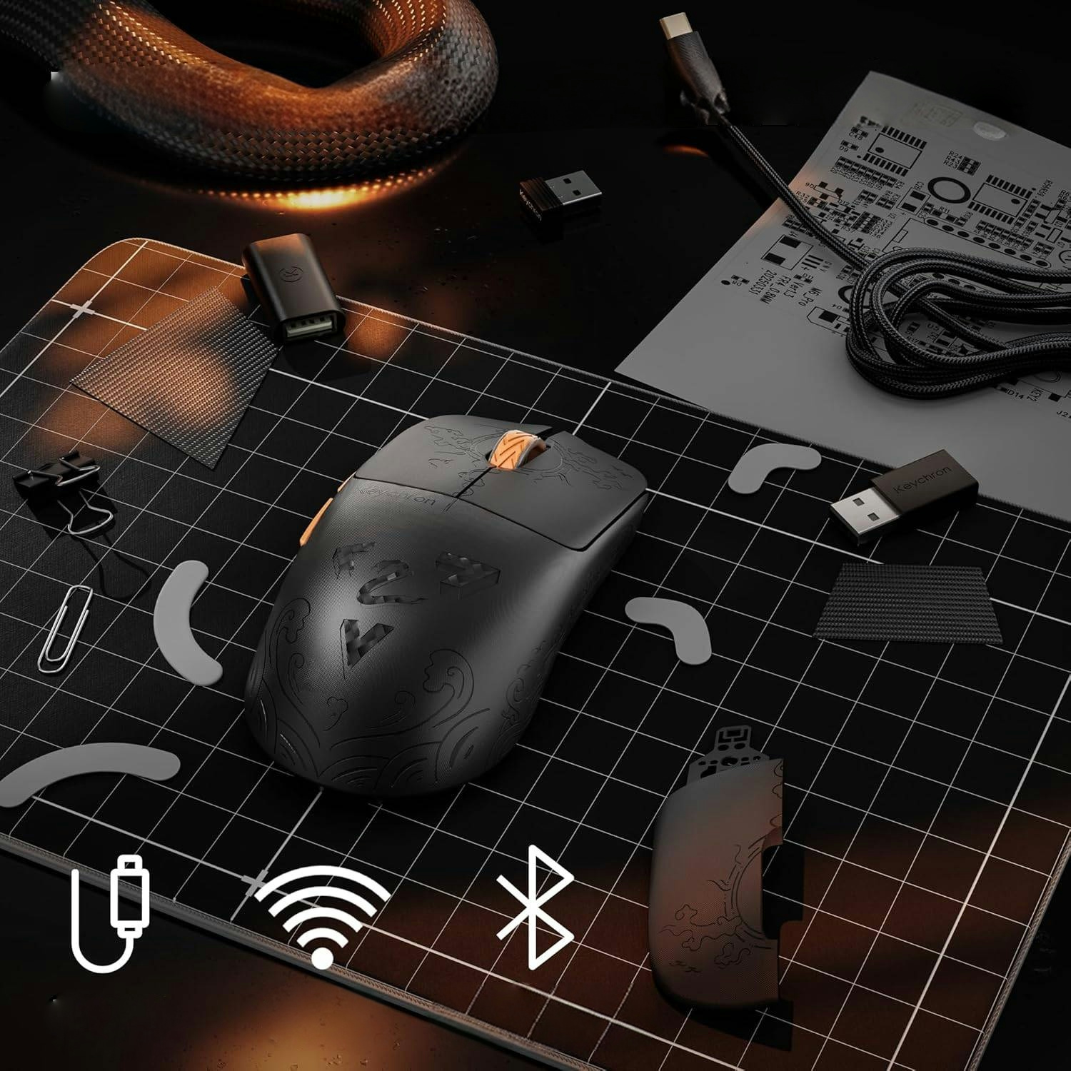 Ratón negro con detalles ornamentados sobre alfombrilla de rejilla junto a dongles USB.