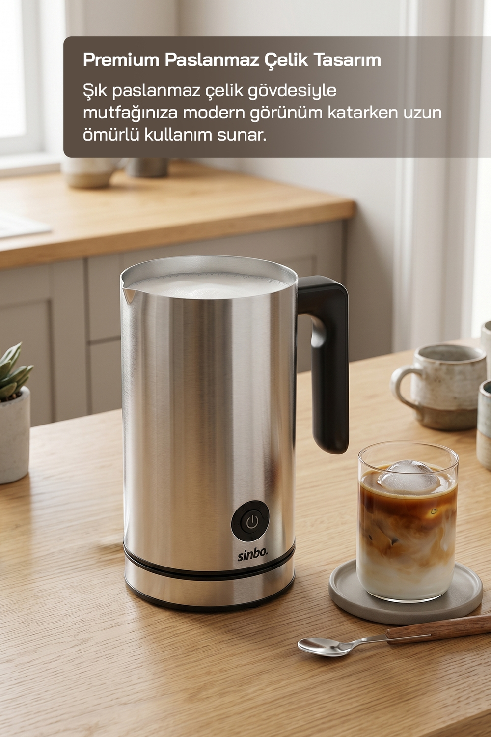 Paslanmaz çelik süt köpürtücü, buzlu kahve bardağı ve ahşap masada kupalar.