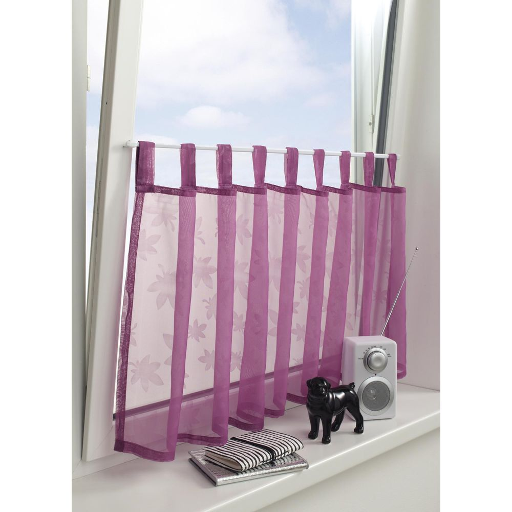 Lila Gardine mit Blumenmuster vor einem Fenster, daneben ein Radio und eine Hundefigur.