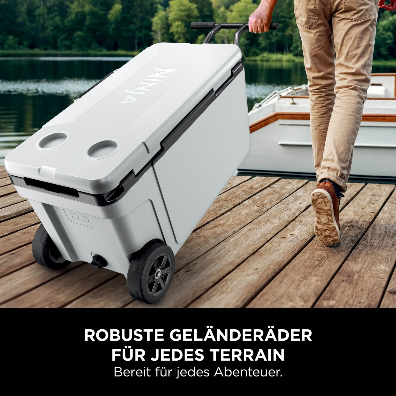 Ein Mann zieht eine weiße Kühlbox auf Rädern über einen Holzsteg.