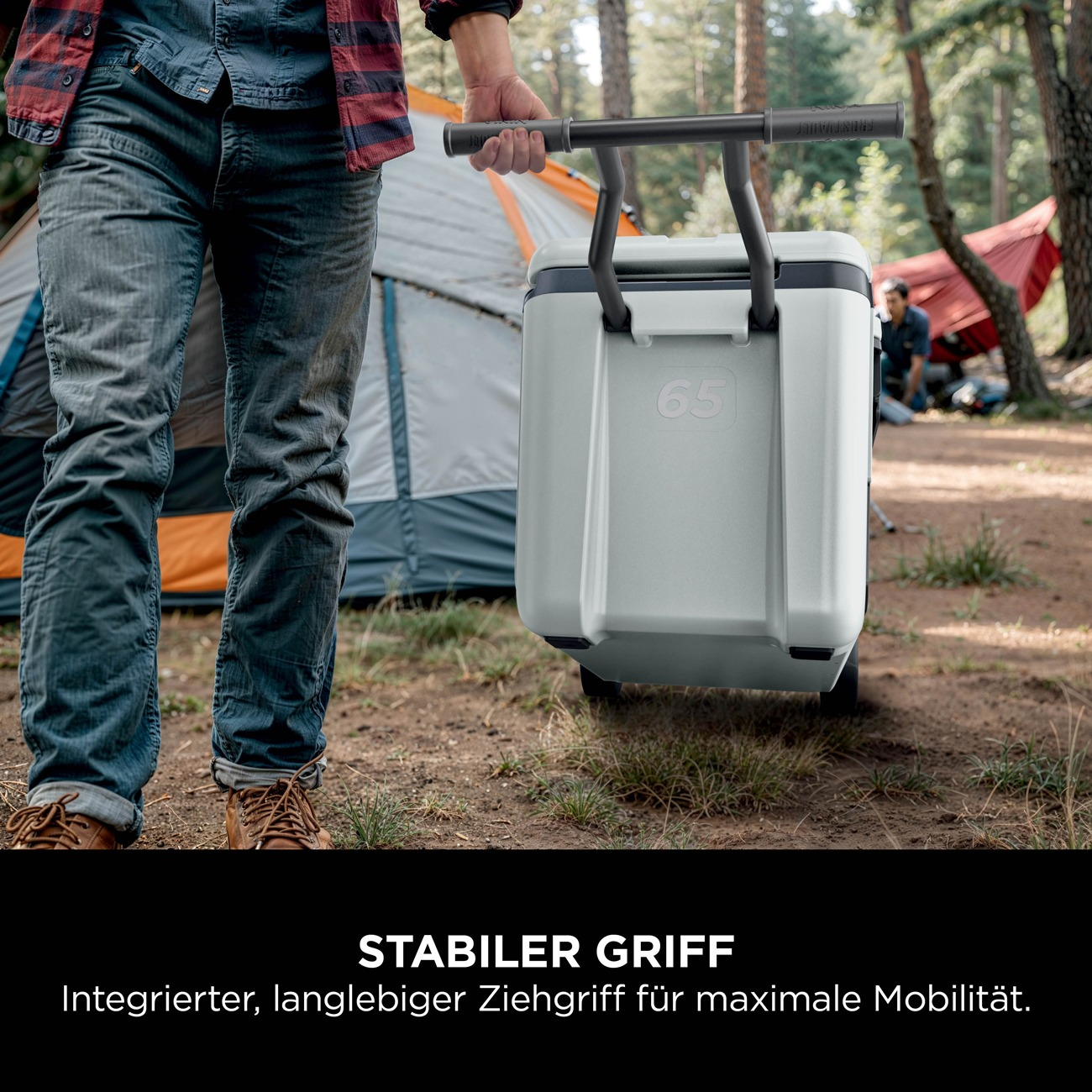 Mann zieht eine graue Kühlbox mit Rädern und ausziehbarem Griff auf einem Campingplatz.