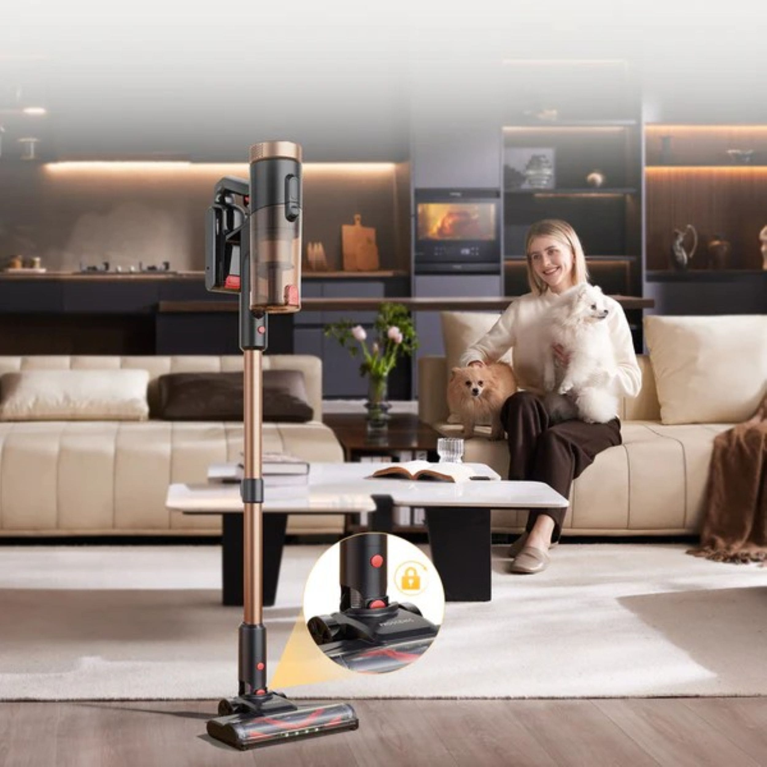 Ein moderner Staubsauger steht neben einem Sofa, auf dem eine Frau mit zwei Hunden sitzt.