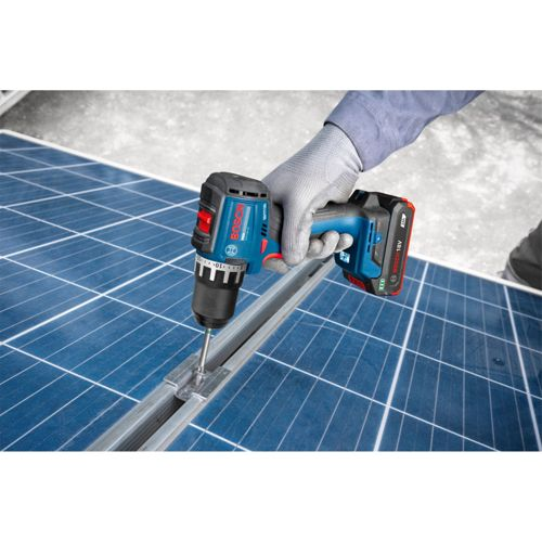 Eine behandschuhte Hand benutzt einen blauen Bosch-Bohrer, um eine Metallhalterung an Solarmodulen zu schrauben.
