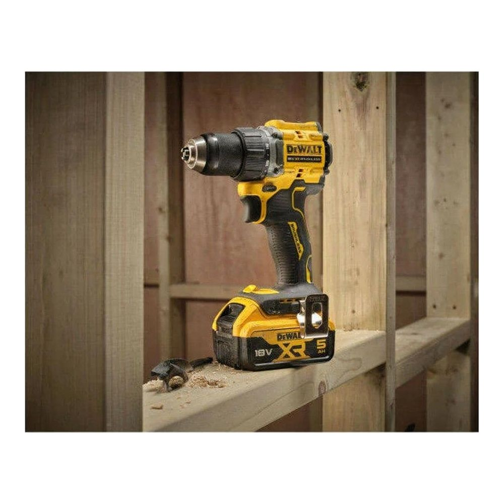 Ein gelber und schwarzer DeWalt Akkuschrauber mit Bohrer und Staub auf einem Holzregal.