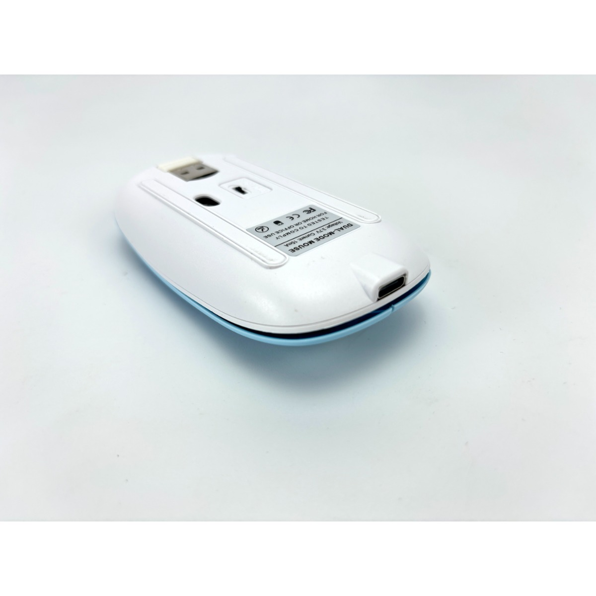 Weiße und blaue Maus mit USB-Anschluss und Ladeanschluss auf der Unterseite.