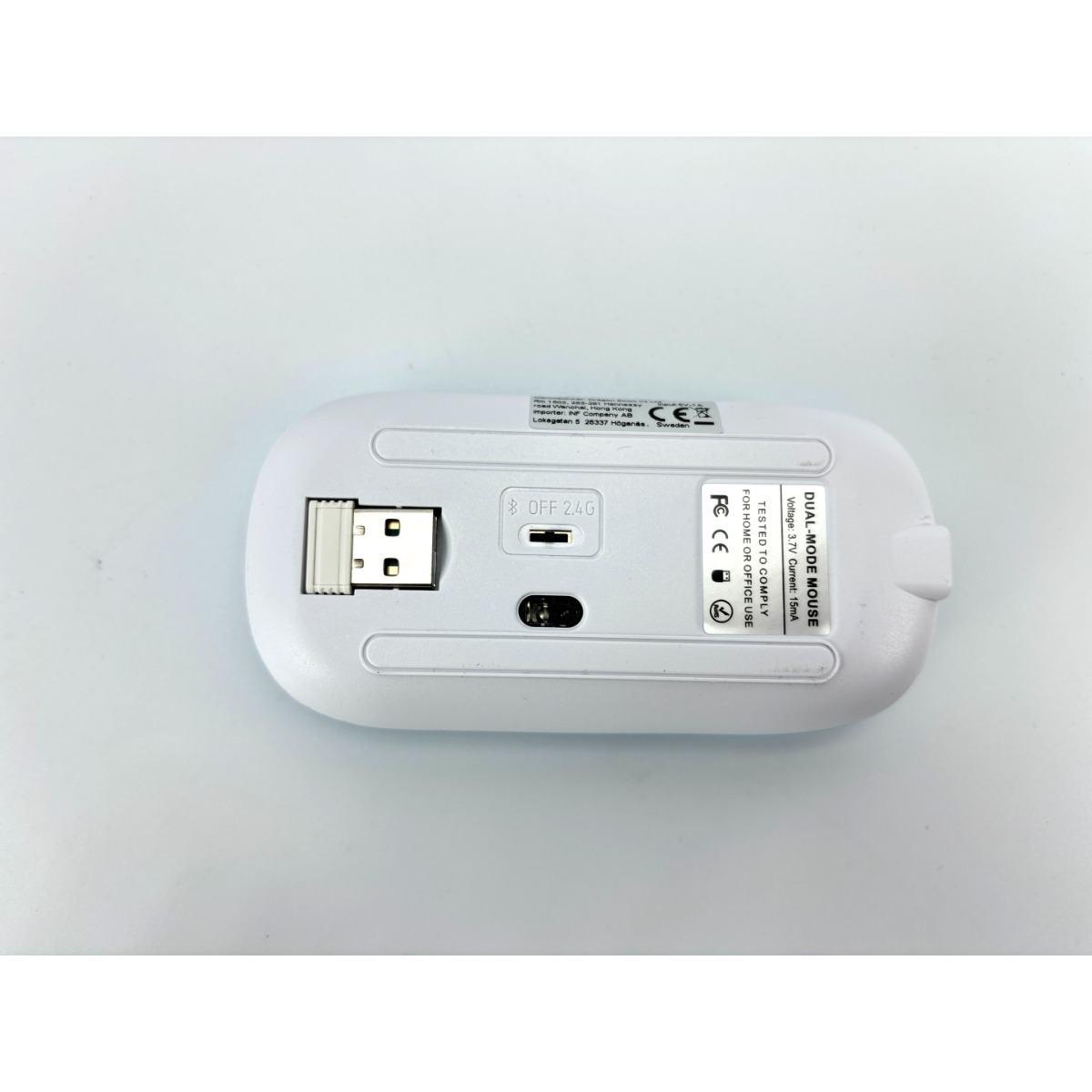 Unterseite einer weißen Maus mit USB-Dongle, Schalter und CE-Kennzeichnung.