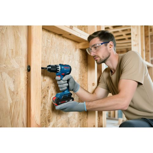 Mann mit Schutzbrille benutzt Bohrmaschine an Holzrahmen.