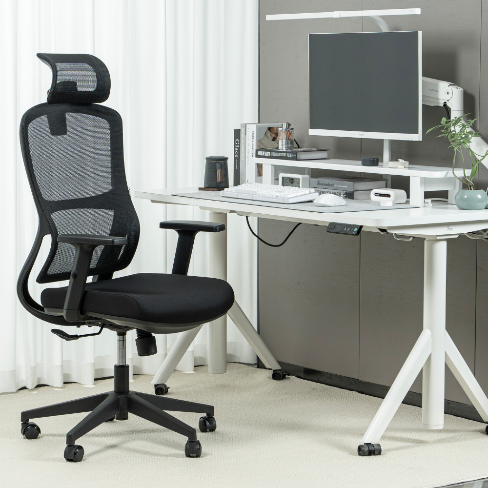 Una sedia da ufficio nera davanti a una scrivania bianca con monitor e forniture.