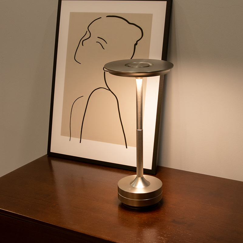 Eine moderne Lampe steht neben einem gerahmten Bild mit einer Strichzeichnung einer Person.