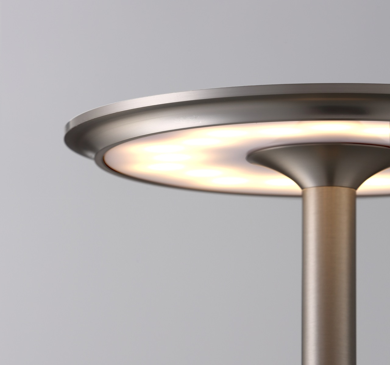 Nahaufnahme einer modernen Lampe mit einem runden, beleuchteten Schirm und einem schlanken Ständer.