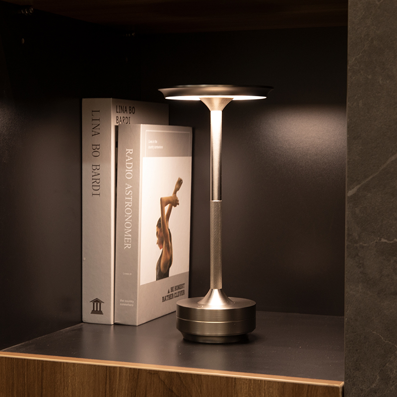 Eine Tischlampe leuchtet neben zwei Büchern auf einem Regal.