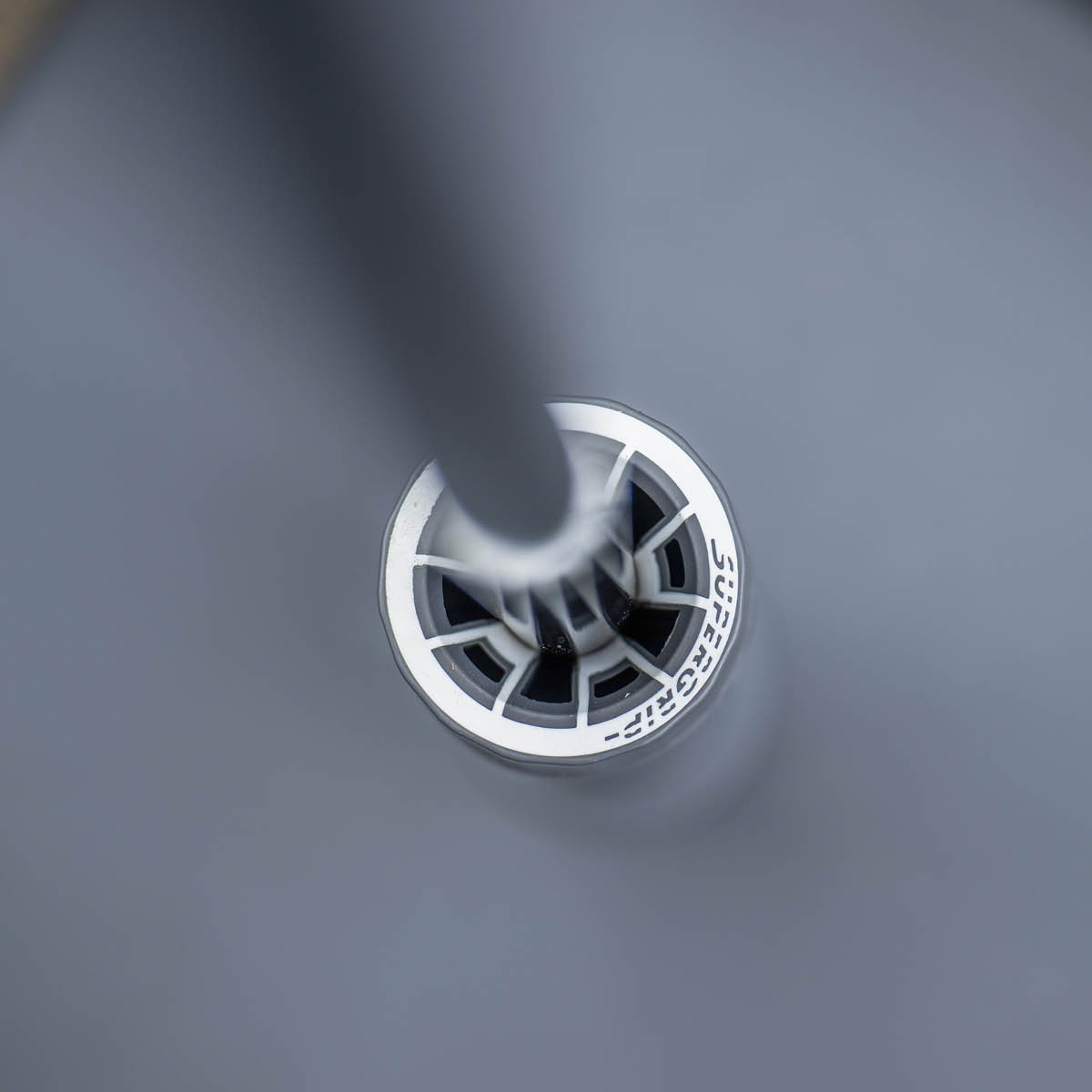 Close-up van een grijze grip met 'SUPERGRIP' tekst in een witte cirkel.