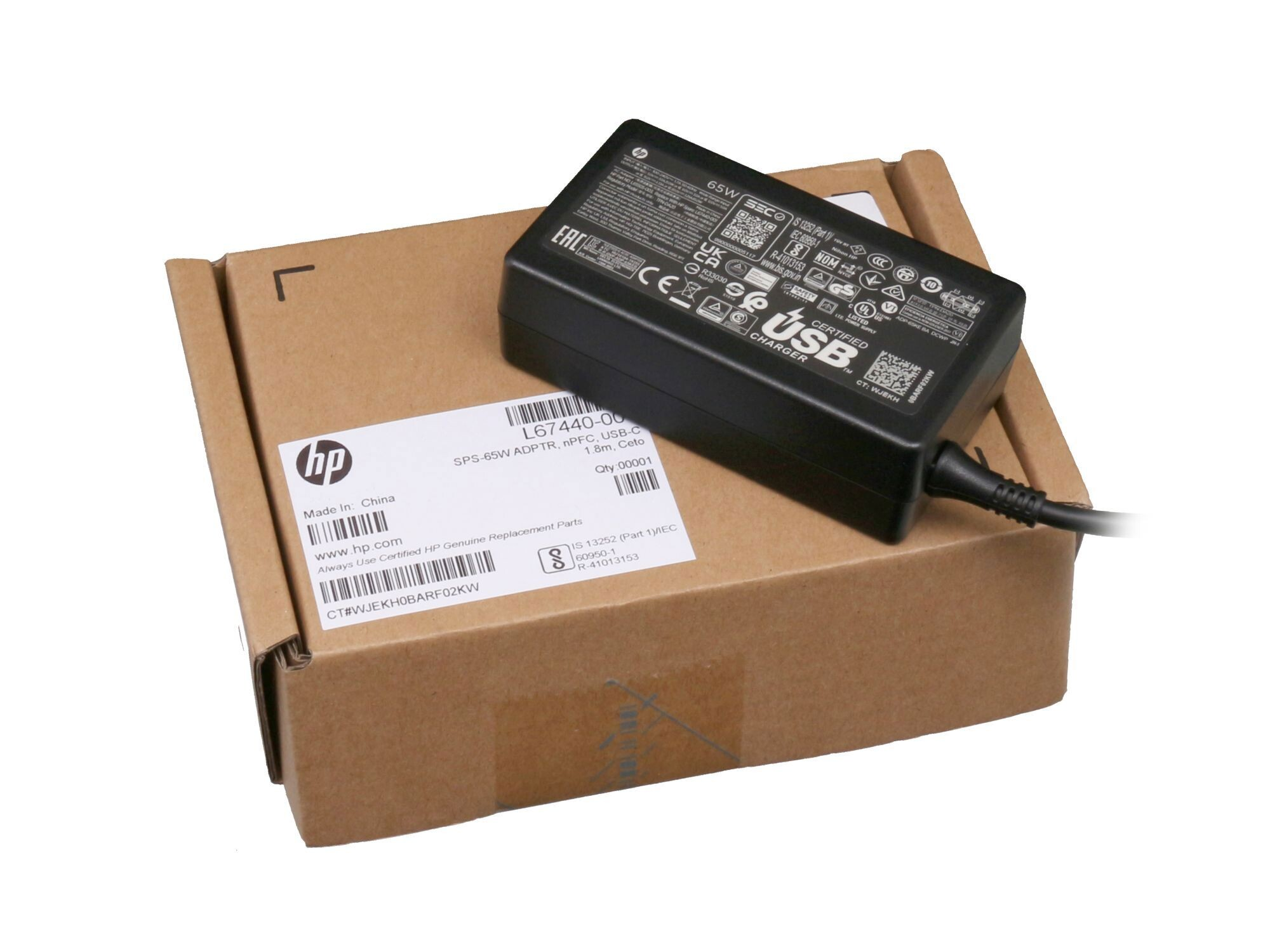 Ein schwarzes HP Netzteil liegt auf einer braunen HP Box.