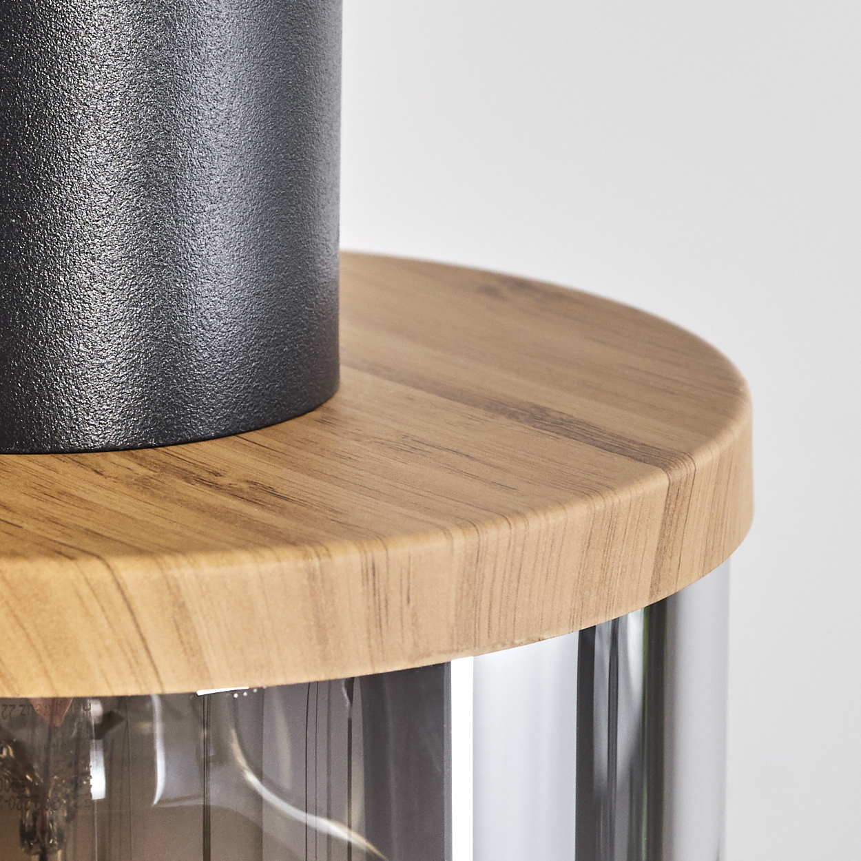 Nahaufnahme einer Lampe mit schwarzem Zylinder, Holzplatte und Metallgehäuse.