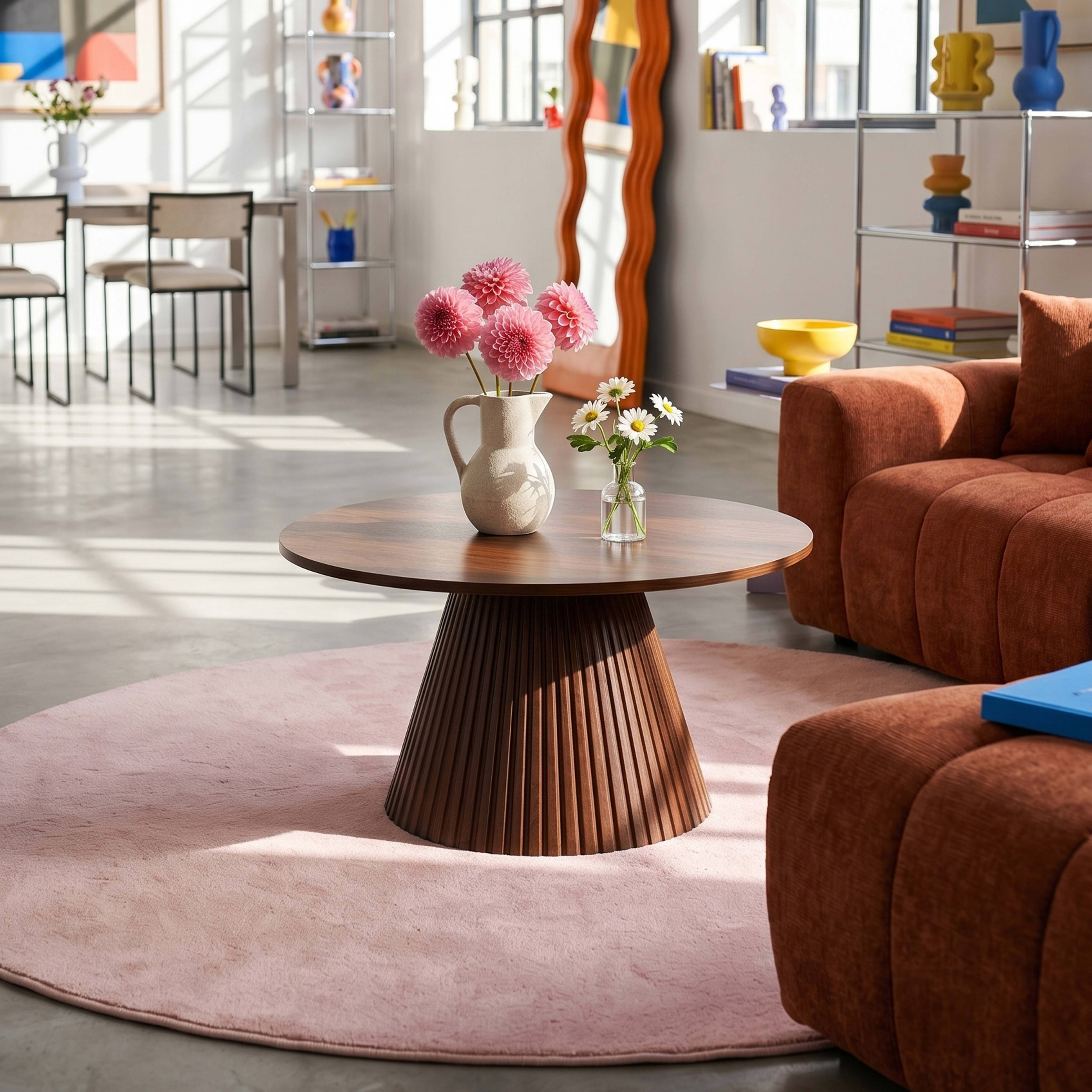 Ein Wohnzimmer mit einem runden Holztisch, zwei Vasen mit Blumen und einem braunen Sofa.