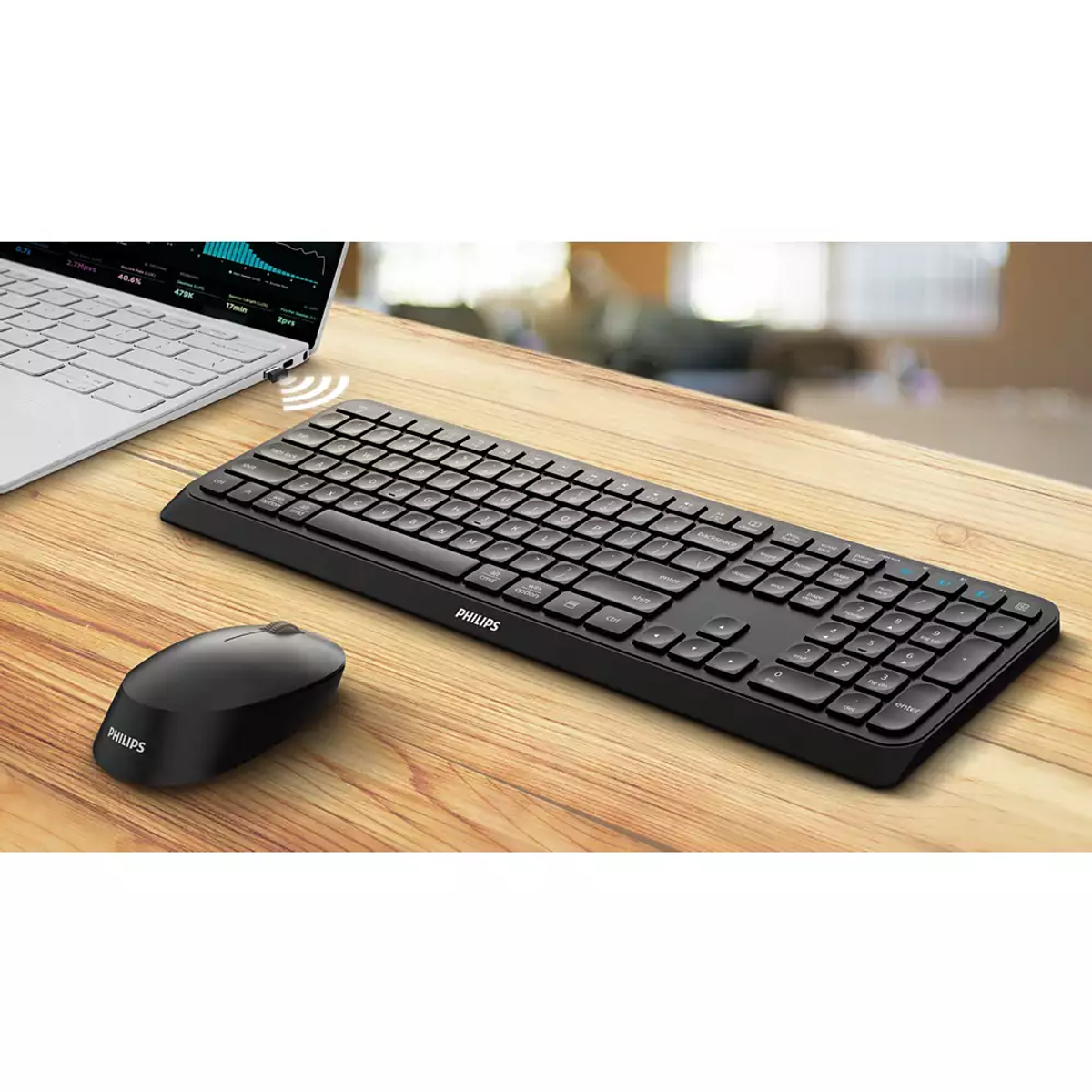Un teclado y ratón Philips negros sobre un escritorio de madera junto a un portátil.