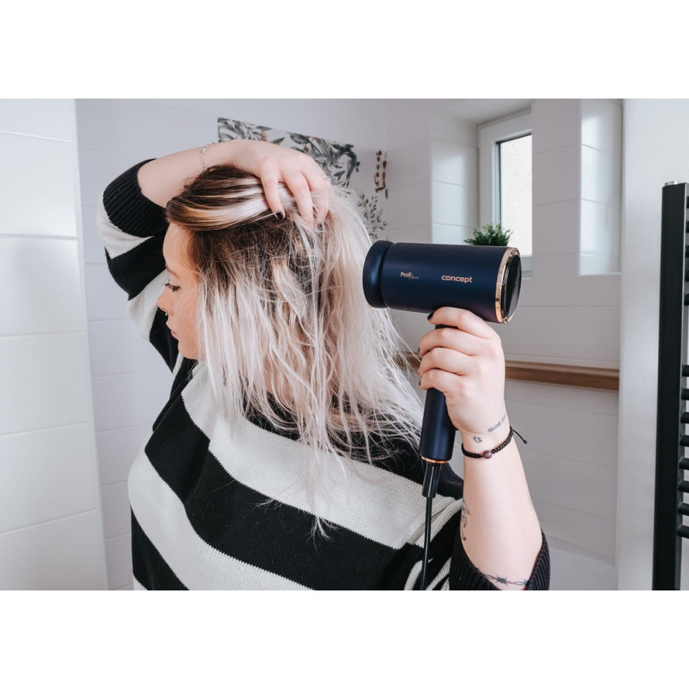 Kobieta suszy blond włosy ciemną suszarką w łazience.