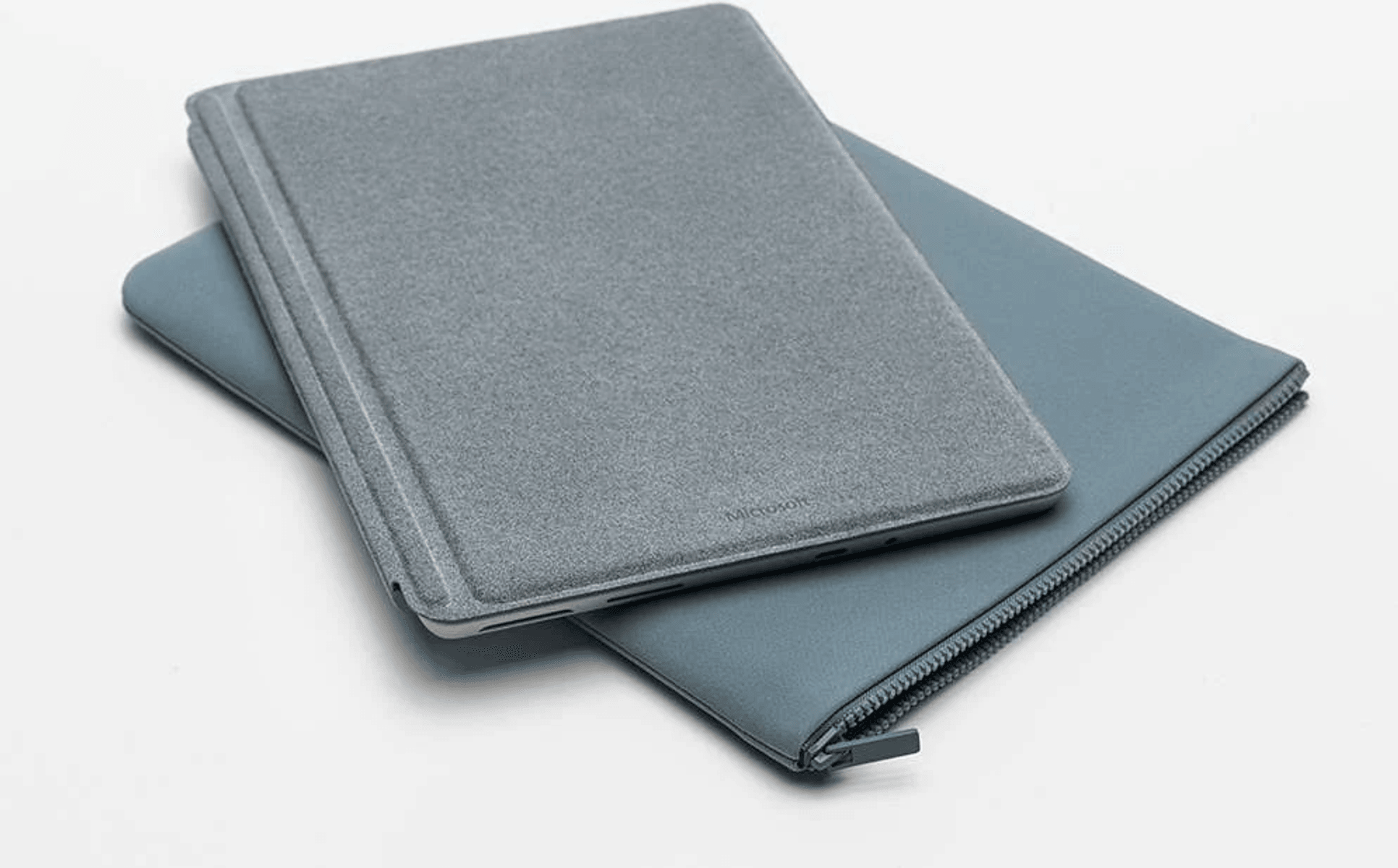 Un soporte gris para portátil descansa sobre un estuche azul con cremallera.