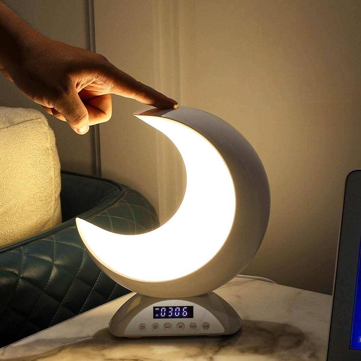Eine Hand berührt eine Mondlampe mit Digitaluhr. Heller Schein.