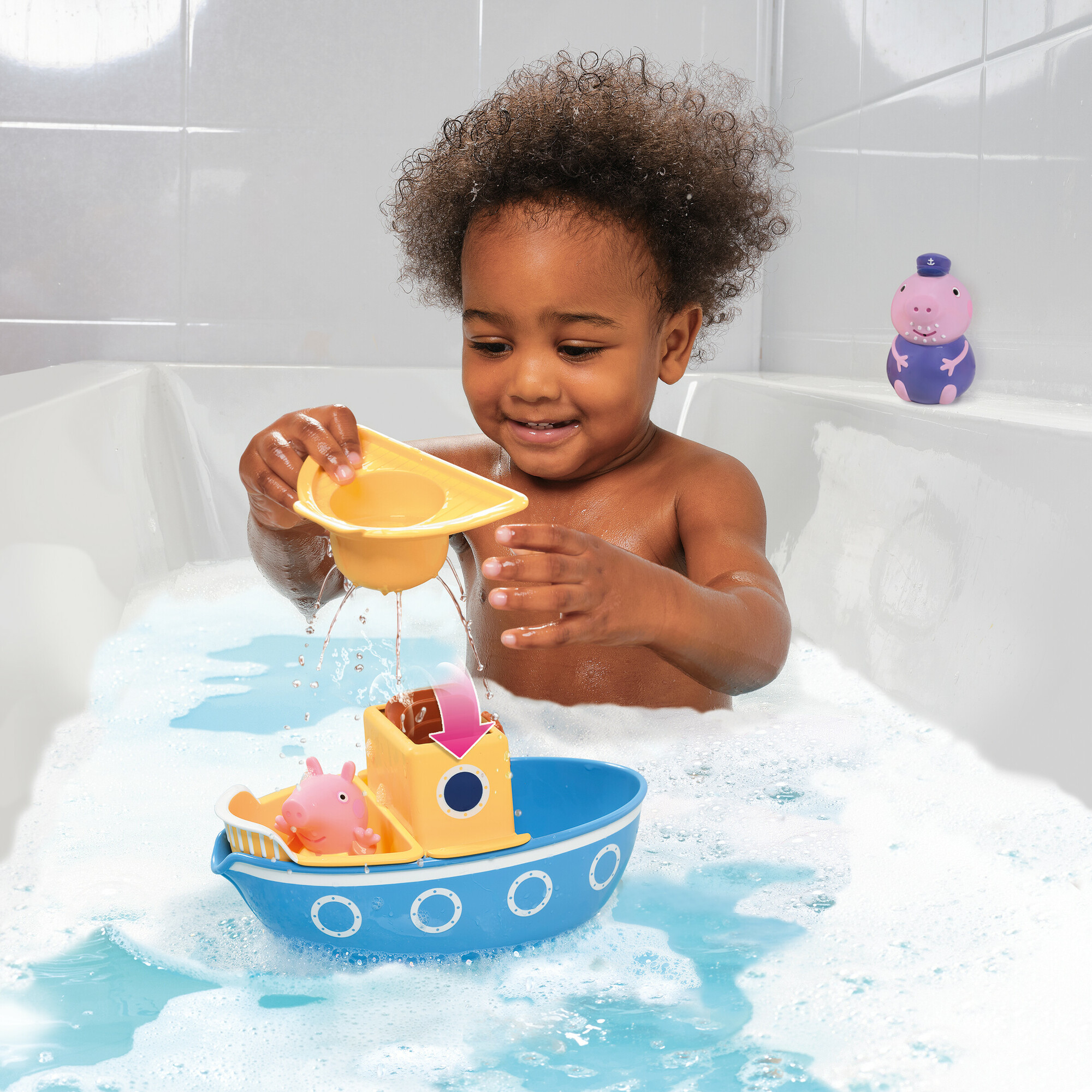 Ein Kleinkind spielt mit einem Spielzeugboot in der Badewanne mit Schaum.
