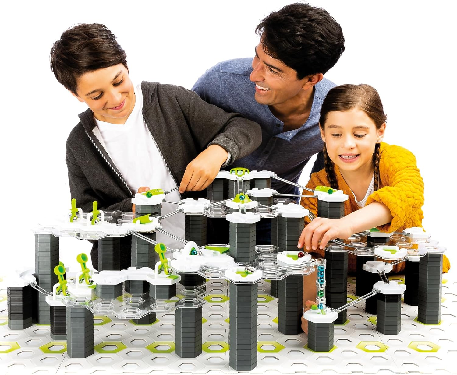Ein Vater und seine zwei Kinder spielen mit einer Murmelbahn und bauen sie auf.
