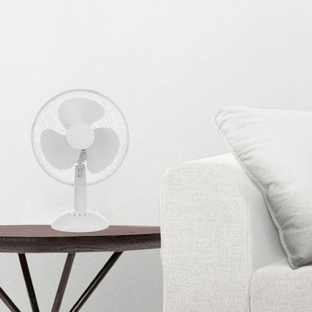 Un ventilatore elettrico bianco si trova su un tavolo di legno scuro accanto a un divano bianco.