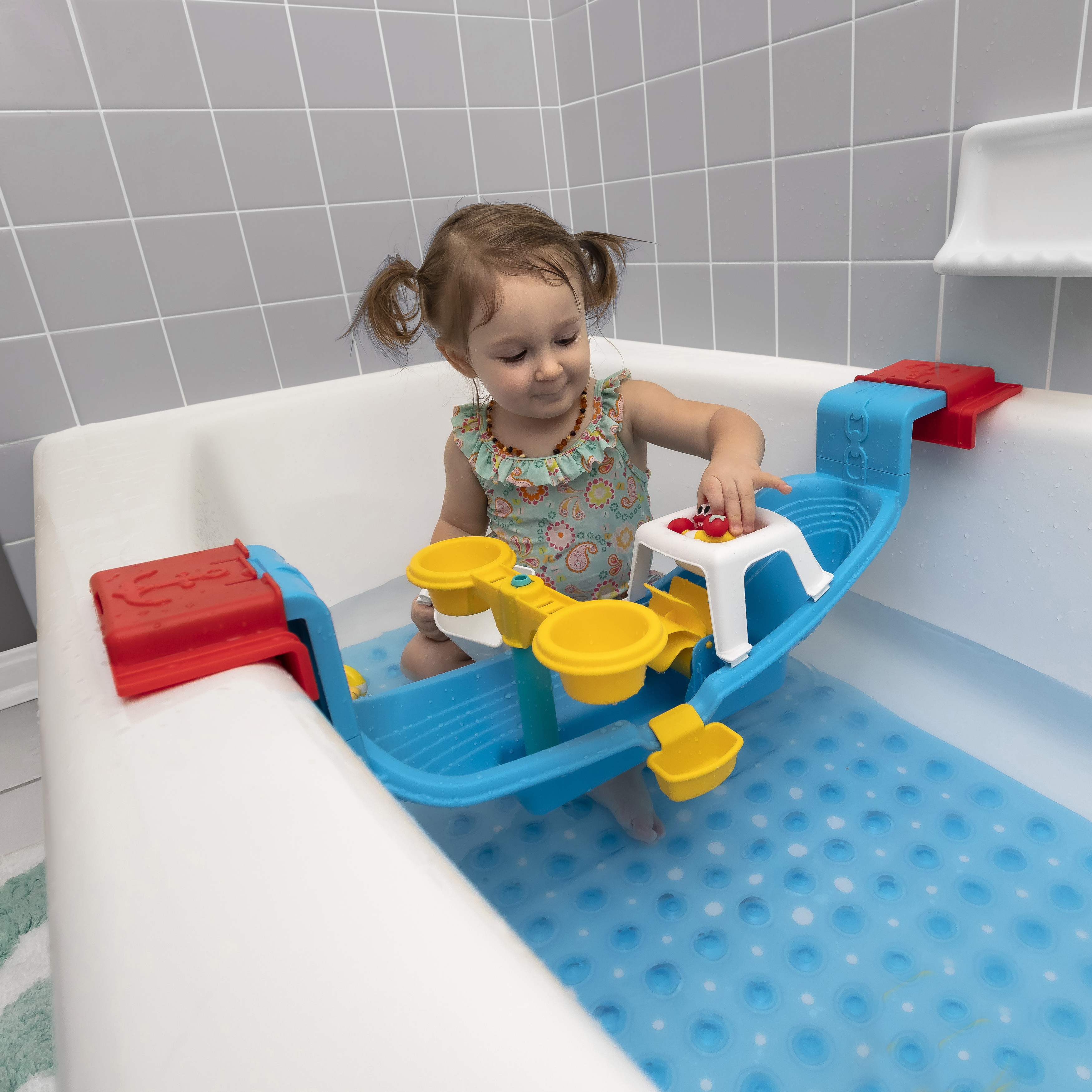 Ein Kleinkind spielt mit einem Spielzeugboot in der Badewanne.