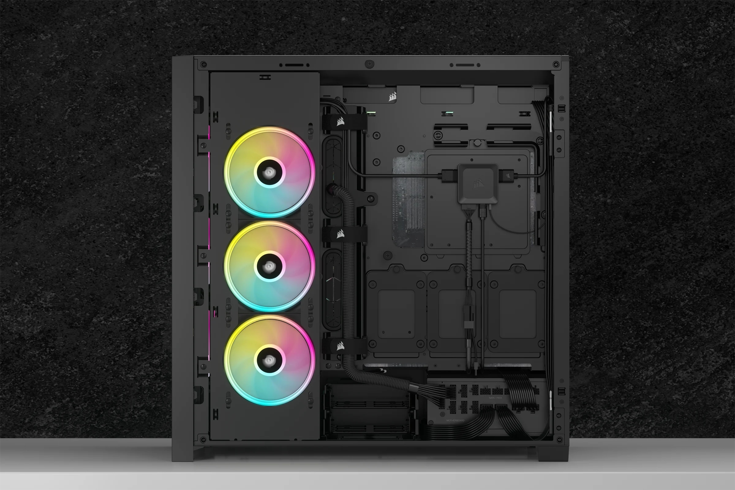 Offenes schwarzes Computergehäuse mit drei RGB-Lüftern links und internen Komponenten rechts.