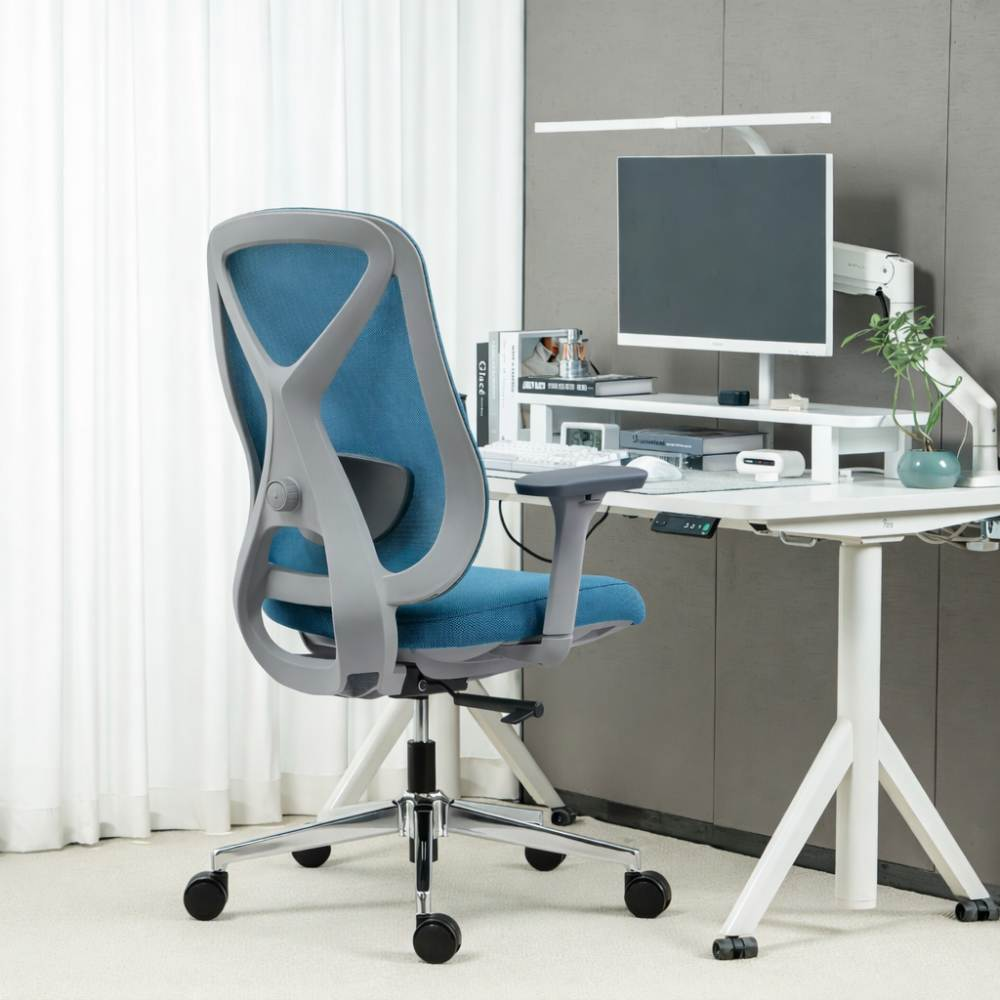 Una sedia da ufficio blu con telaio grigio è accanto a una scrivania bianca con computer.