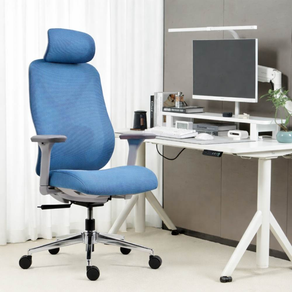 Una sedia da ufficio ergonomica blu davanti a una scrivania con monitor.