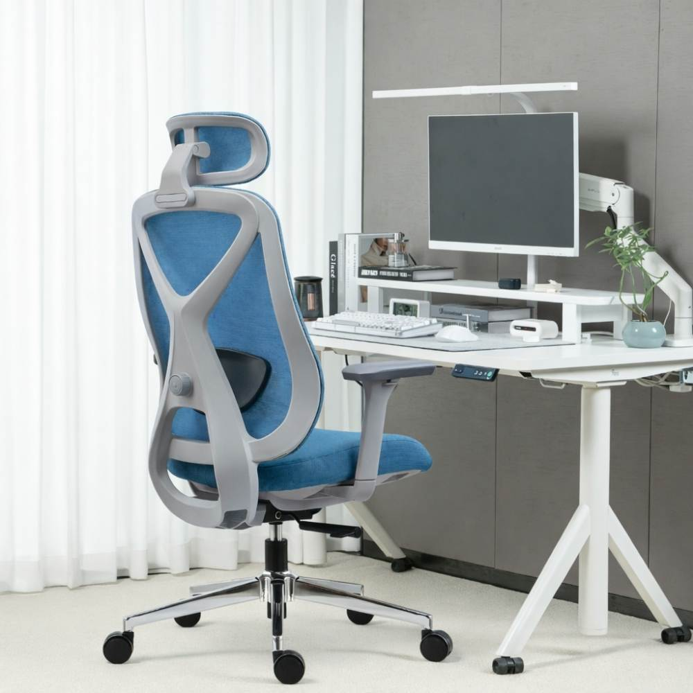 Una sedia da ufficio ergonomica blu accanto a una scrivania bianca con attrezzatura informatica.