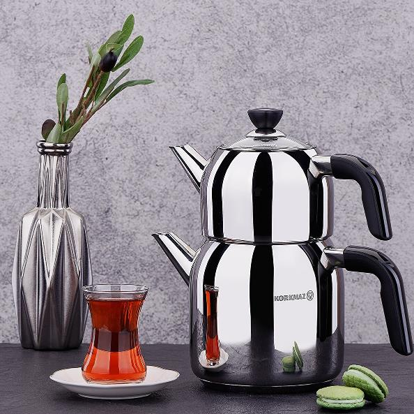 Gümüş çaydanlık, çay bardağı, zeytin dalı vazosu ve makaronlar.