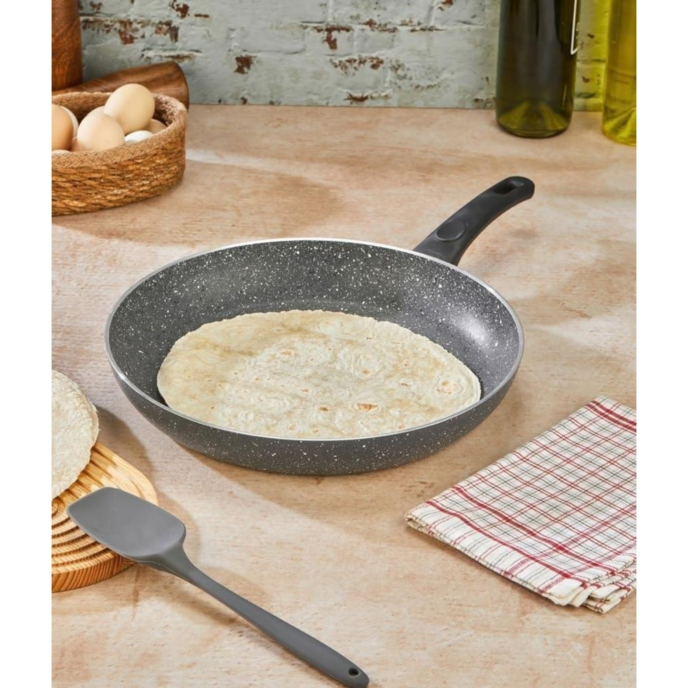 Noktalı tavada pişen yuvarlak tortilla tezgaha üzerinde. Sepette yumurtalar.