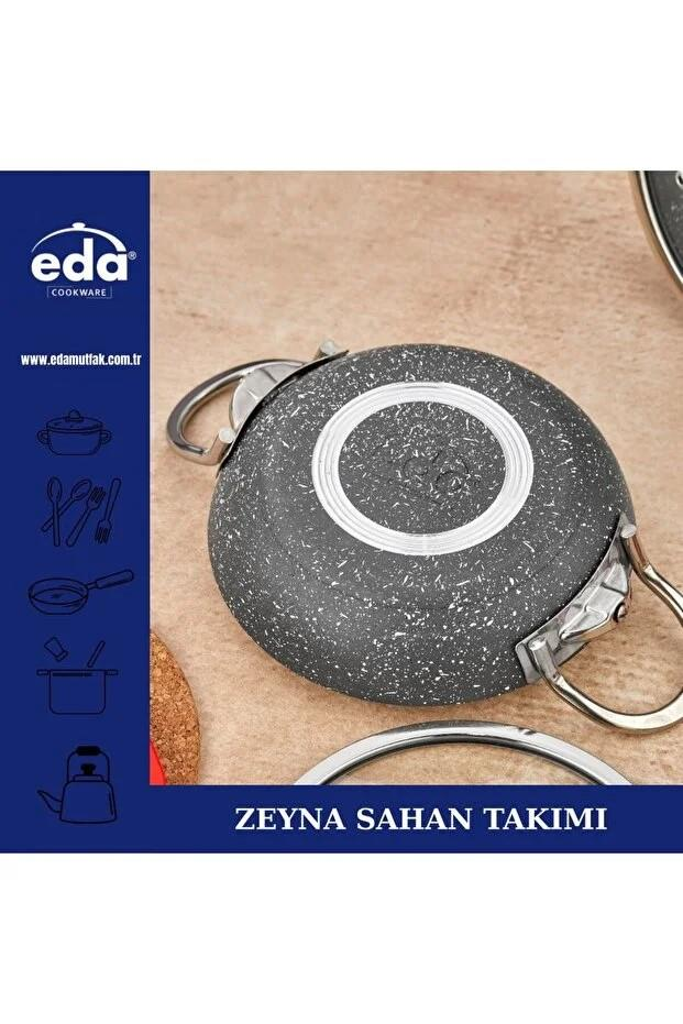 Gümüş saplı gri tencere, üzerinde logo bulunan bej zeminde.
