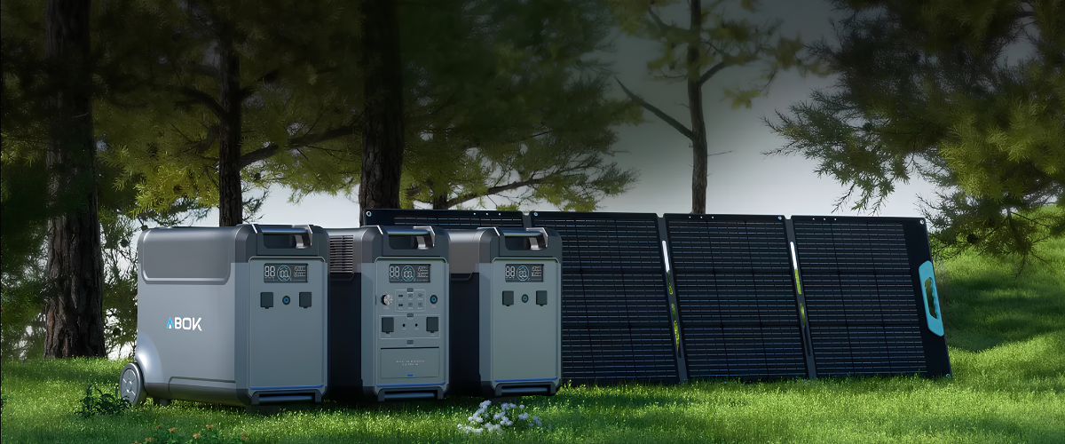 Trzy szare elektrownie stoją obok czarnych paneli słonecznych na zielonym trawniku.