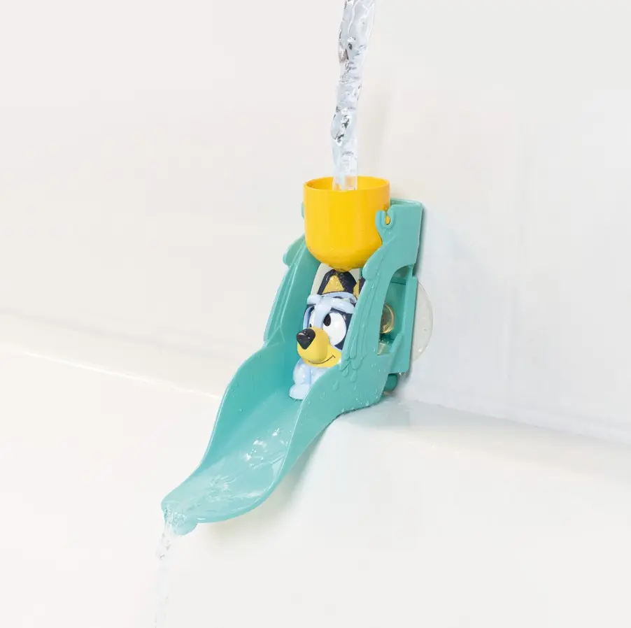 Un juguete de baño de Bluey se desliza por un tobogán turquesa mientras fluye el agua.