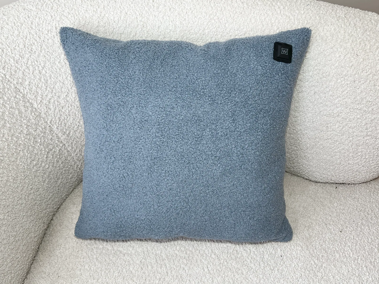 Ein blauer Kissen mit Textur auf einem weißen Sofa.