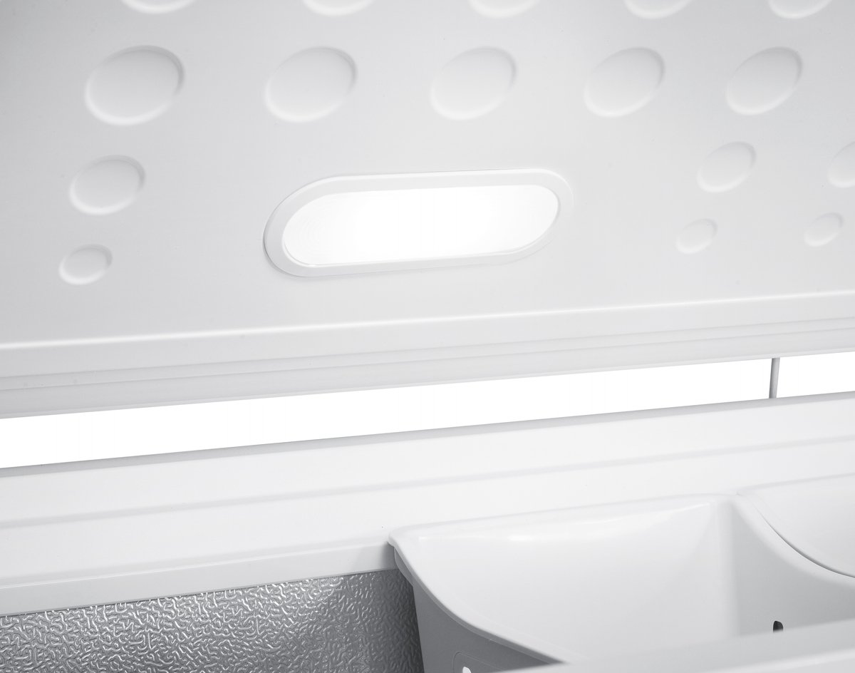 Intérieur d'un congélateur blanc avec éclairage et compartiments.