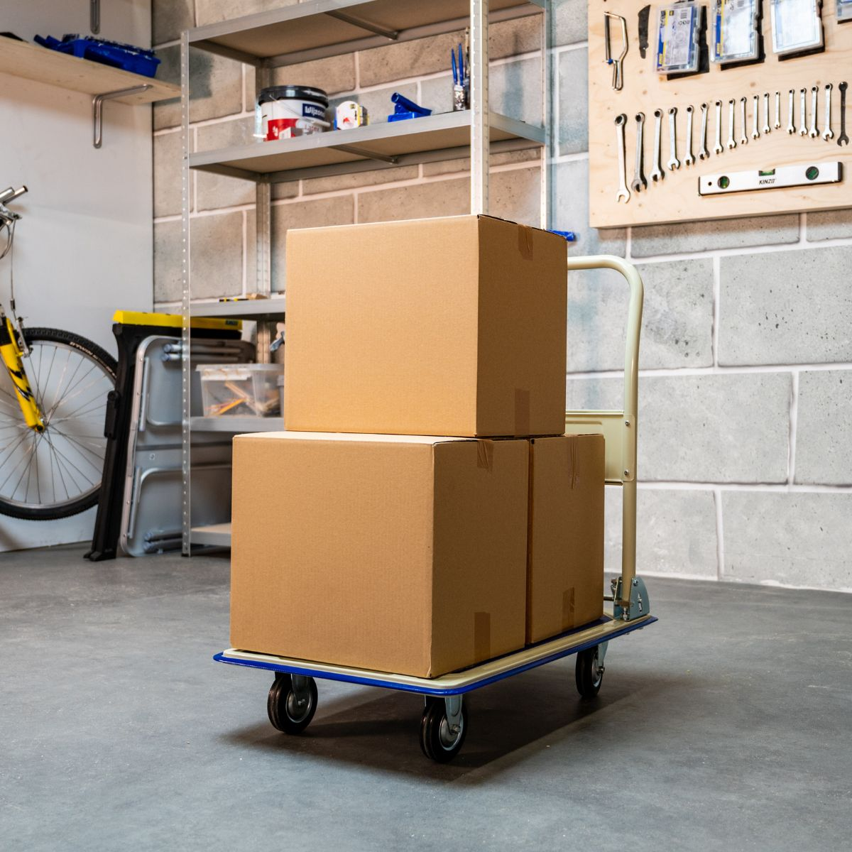 A trolley with three cardboard boxes sits on a concrete floor.