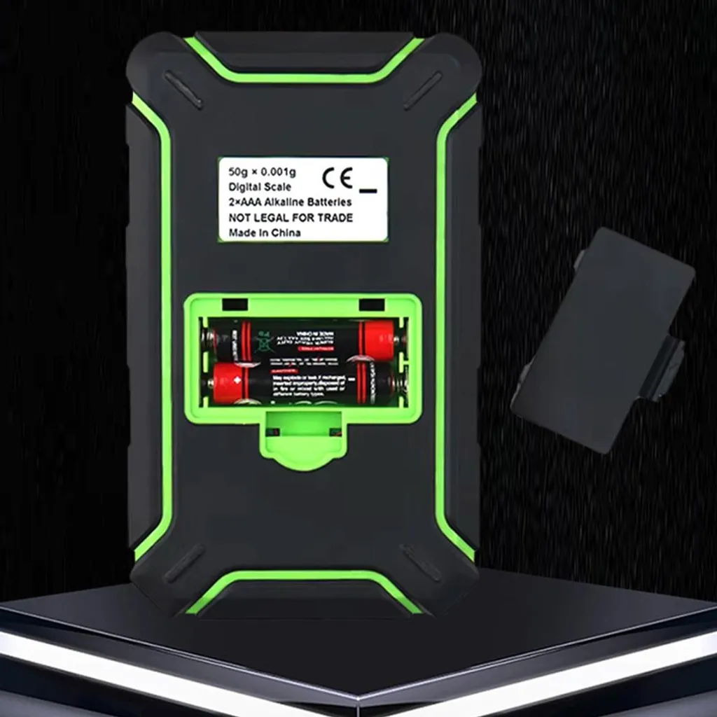 Rückseite einer schwarzen Digitalwaage mit grünen Akzenten, zwei AAA-Batterien.