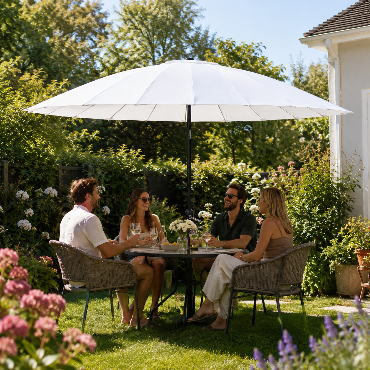 Vier mensen zitten aan een tafel onder een parasol in een tuin.