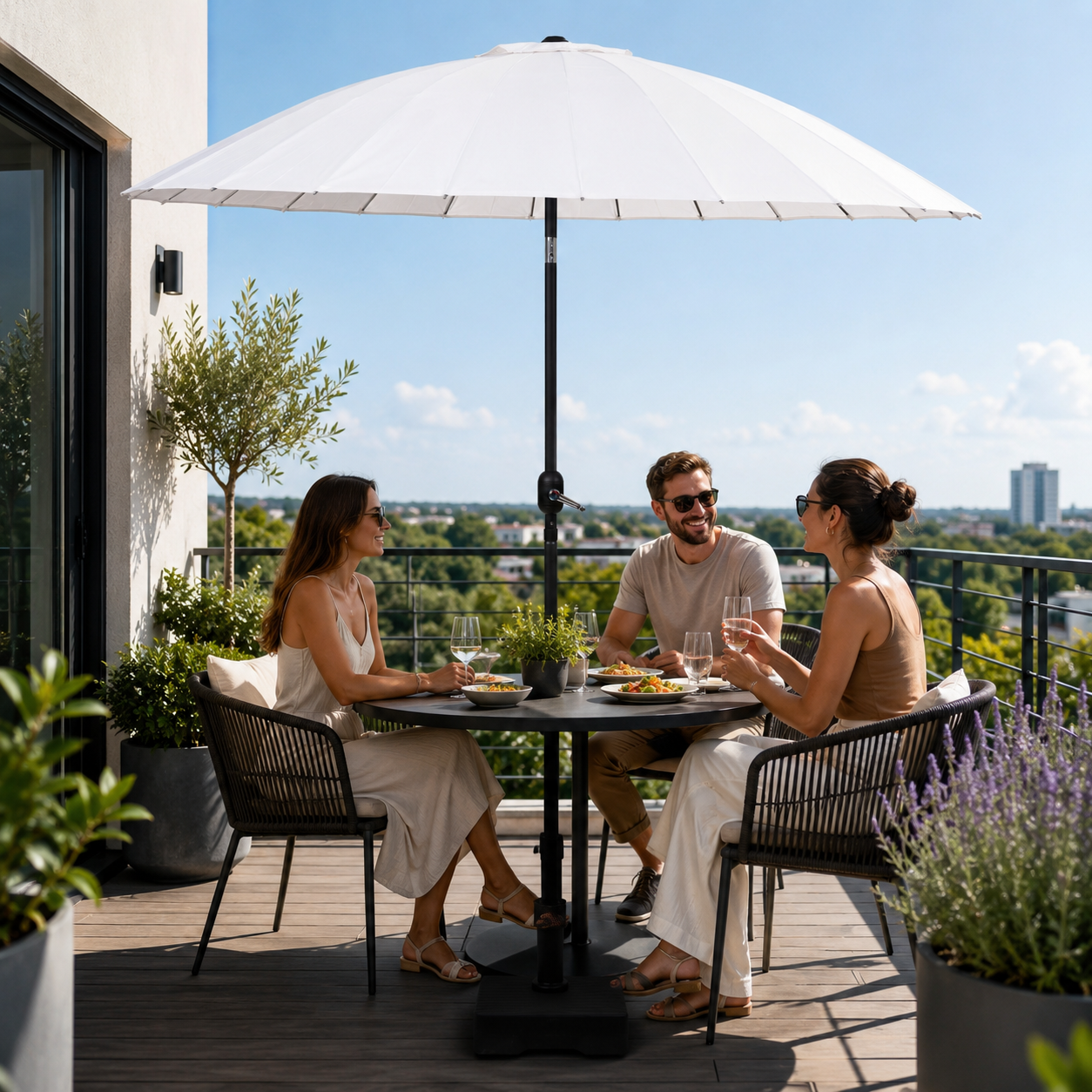 Drie mensen dineren buiten op een balkon onder een grote witte parasol.