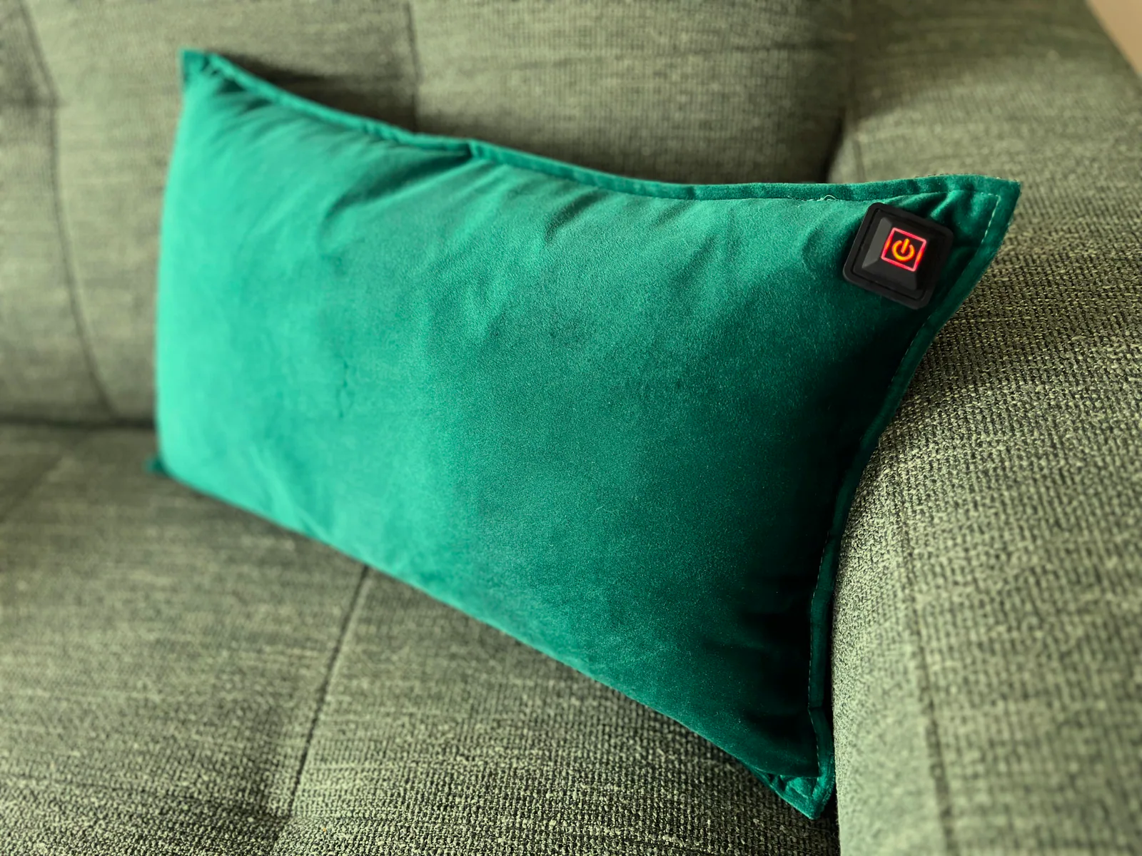 Ein grünes Kissen mit einem Power-Symbol auf einem Sofa.